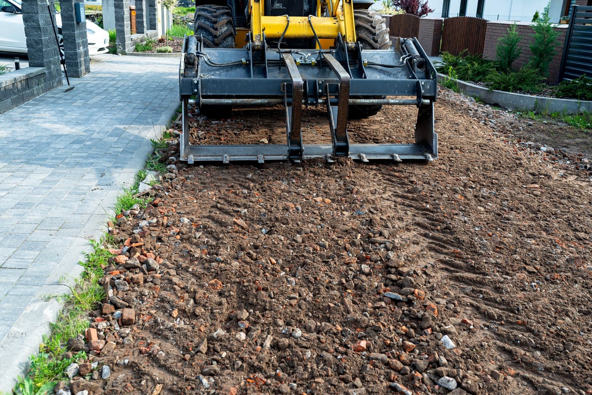 Backhoe loader leveling dirt road for construction site preparation