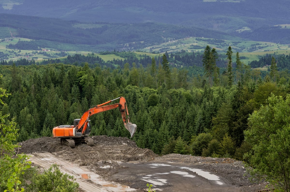 Excavator working in mountainous terrain during land clearing